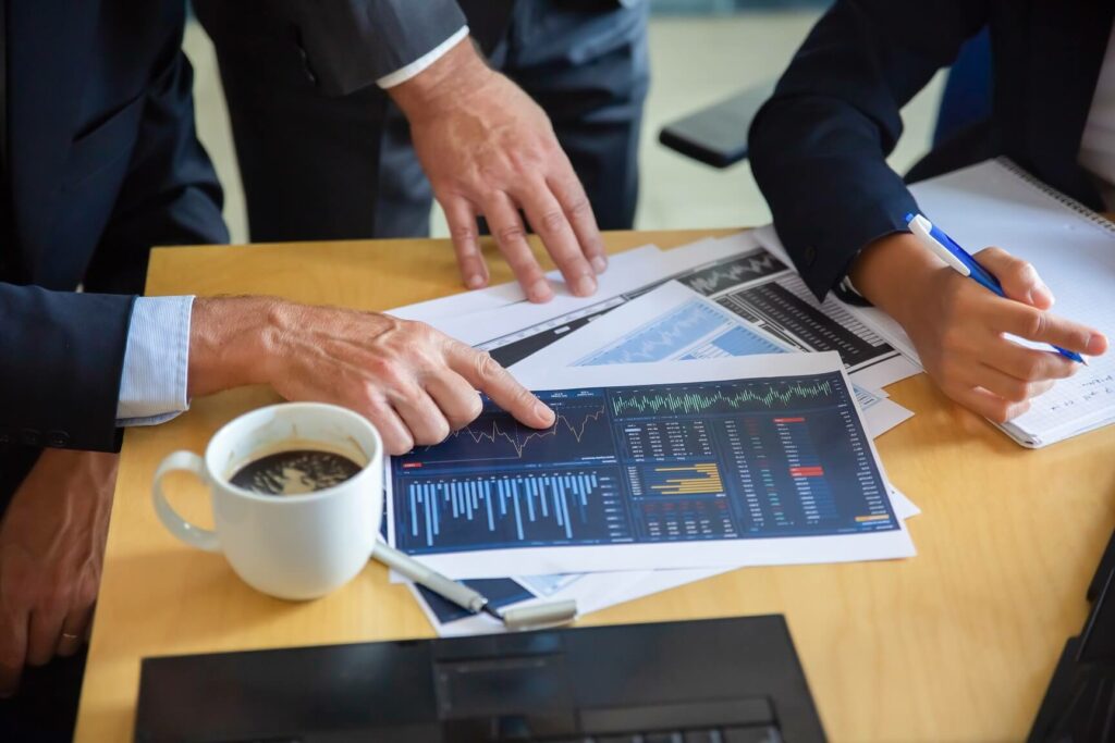 unrecognizable-businessman-pointing-printed-chart-showing-graph-colleagues-professional-content-partners-making-notes-statistics-cooperation-communication-partnership-c unrecognizable-businessman-pointing-printed-chart-showing-graph-colleagues-professional-content-partners-making-notes-statistics-cooperation-communication-partnership-c